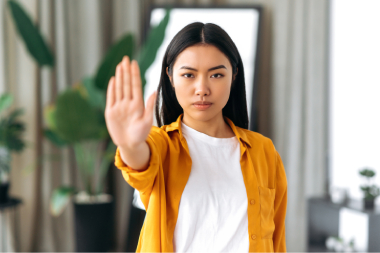 Eine asiatische Frau zeigt mit flacher Hand die Geste: Stopp!