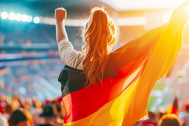 Frau mit einer Deutschland-Fahne jubelnd im Fußball-Stadion.